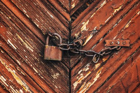 Téléchargez les photos : Vieux cadenas rouillé corrodé avec chaîne sur porte de grange de ferme en bois comme fond - en image libre de droit