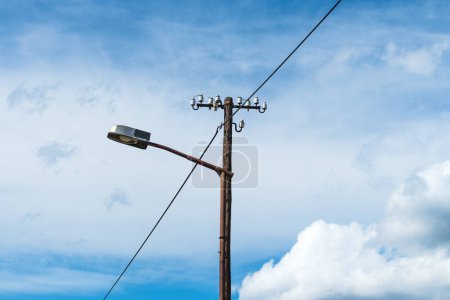 Photo for Old street light lamp and electricity pole against blue sky - Royalty Free Image