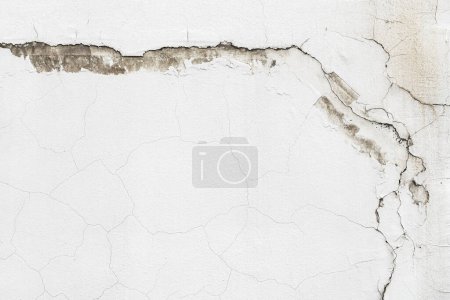 Foto de Antigua pared de cemento blanco con grietas intrincadas y patrones únicos. La textura áspera y el fondo angustiado con espacio de copia. - Imagen libre de derechos