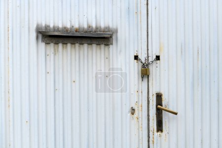 Téléchargez les photos : Ancienne porte métallique industrielle usée avec chaîne et cadenas comme arrière-plan - en image libre de droit