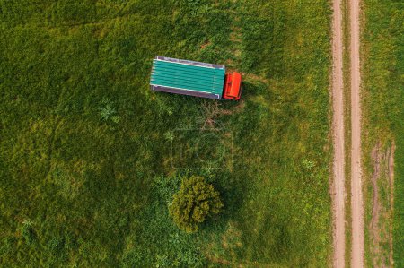 Photo for Aerial shot of apiary truck and trailer with beehive boxes in field in spring, drone pov top view - Royalty Free Image