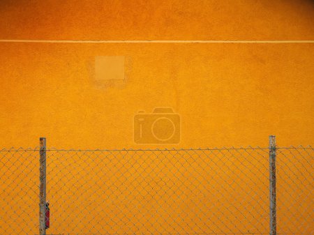 Téléchargez les photos : Modèle de clôture de maillon de chaîne contre le mur jaune vibrant comme élément de conception de fond, espace de copie inclus - en image libre de droit