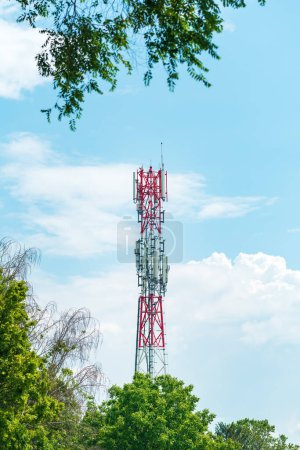 Téléchargez les photos : Pylône de station de base de téléphonie mobile avec antennes et autres équipements de télécommunication vus à travers les arbres du parc - en image libre de droit