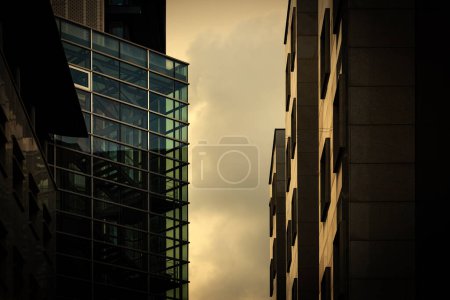 Téléchargez les photos : Détail de l'immeuble de bureaux d'entreprise moderne avec des surfaces de façade en marbre et en verre éclairées par la lumière du coucher du soleil, foyer sélectif - en image libre de droit