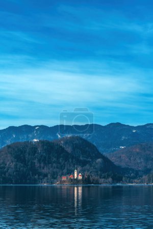 Téléchargez les photos : Lac de Bled dans la froide matinée de février avec le célèbre monument, l'Assomption de l'église Maria en arrière-plan, accent sélectif - en image libre de droit