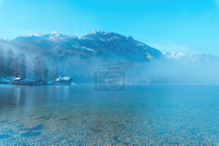 Téléchargez les photos : Lac Bohinj paysage dans la matinée d'hiver, brouillard se levant sur l'eau glaciaire propre dans le parc national slovène Triglav et célèbre destination de voyage - en image libre de droit