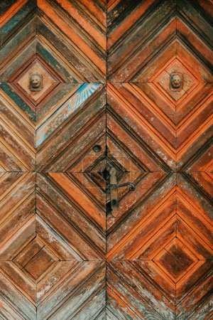 Téléchargez les photos : Vieille porte en bois usé avec motif diamant symétrique et poignée rouillée comme fond - en image libre de droit