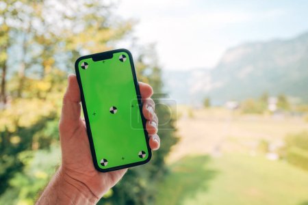 Photo for Male hand holding smart phone with mockup green screen, selective focus - Royalty Free Image