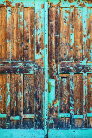 Photo for Old wooden gate doorway with blue paint peeling off, worn door with metallic handle - Royalty Free Image