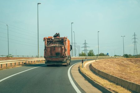 Téléchargez les photos : Camion à ordures orange sur autoroute, vue arrière avec mise au point sélective - en image libre de droit