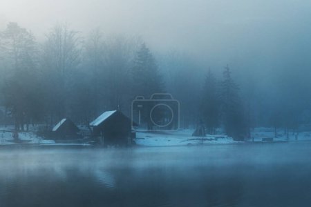 Foto de Bohinj casa de botes lago en el paseo marítimo en la nebulosa mañana de invierno con cabañas de madera y muelles, enfoque selectivo - Imagen libre de derechos