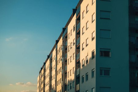 Téléchargez les photos : Immeuble d'appartements en copropriété résidentiel avec fenêtres orientées côté ouest éclairées par le soleil couchant, vue à angle bas - en image libre de droit