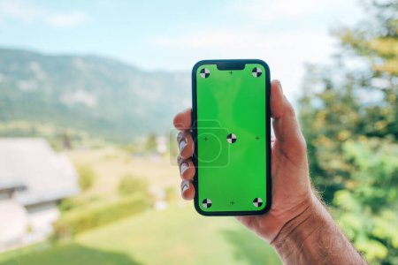 Foto de Mano masculina que sostiene el teléfono inteligente con la pantalla verde de la maqueta, foco selectivo - Imagen libre de derechos