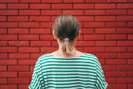 Photo for Dead end concept, rear view of casual brunette female facing the red brick wall, selective focus - Royalty Free Image