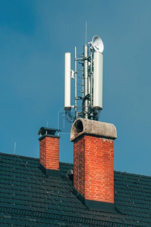 Photo for Mobile telephony base station and signal repeater antenna on building roof, telecommunication technology equipment, selective focus - Royalty Free Image