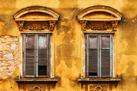 Téléchargez les photos : Vieilles fenêtres avec volets en bois sur la façade jaune usée du bâtiment, détail de la vieille ville de Crikvenica en Croatie - en image libre de droit
