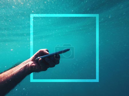 Foto de Hombre usando dispositivo de teléfono inteligente bajo el agua en el mar azul profundo con el espacio de copia de marco de moda durante las vacaciones de verano enfoque selectivo - Imagen libre de derechos