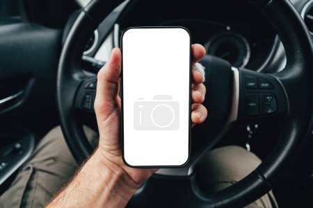 Photo for Driver app mockup with blank smartphone screen over steering wheel, man holding mobile phone device in car, selective focus - Royalty Free Image