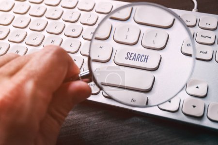 Foto de Tecla de botón de búsqueda en el teclado del ordenador visto a través de lupa de lupa, enfoque selectivo - Imagen libre de derechos
