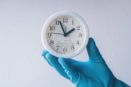 Photo for Doctor holding white alarm clock in hand with glove, selective focus - Royalty Free Image