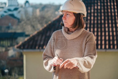 Téléchargez les photos : Architecte femme prenant des notes et des remarques lors de l'inspection du chantier, accent sélectif - en image libre de droit