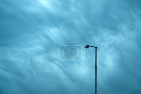 Foto de Farola en un poste alto contra el cielo dramático malhumorado, composición minimalista - Imagen libre de derechos