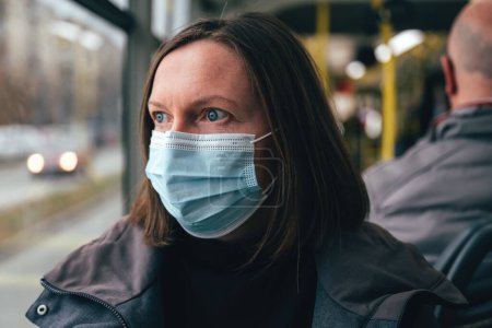 Photo for Woman with protective face mask riding public transportation bus in winter, selective focus - Royalty Free Image