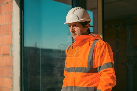 Foto de Ingeniero de construcción con casco blanco protector y chaqueta naranja de alta visibilidad en el sitio, enfoque selectivo - Imagen libre de derechos