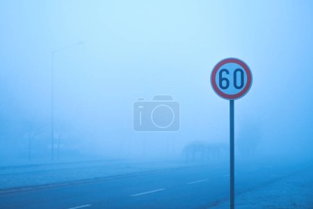 Téléchargez les photos : Panneau de limitation de vitesse dans le brouillard matin d'hiver, mise au point sélective - en image libre de droit