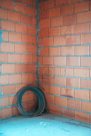 Foto de Rollo de acero plano en el sitio de construcción con paredes construidas de bloques de arcilla térmica, espacio de copia incluido - Imagen libre de derechos