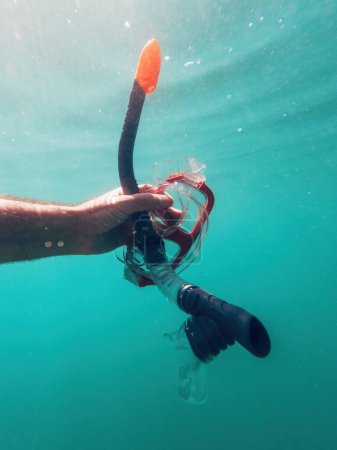 Foto de Hombre sosteniendo máscara de snorkel bajo el agua mientras nada en el océano, enfoque selectivo - Imagen libre de derechos