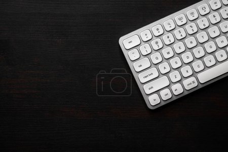 Photo for Modern white aluminum computer keyboard on dark wooden home office desk as copy space, top view - Royalty Free Image