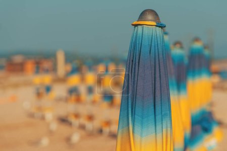 Téléchargez les photos : Parasols de plage pliés et colorés sur la côte de la mer Adriatique en été ensoleillé matin, vacances et arrière-plan de vacances avec espace de copie - en image libre de droit