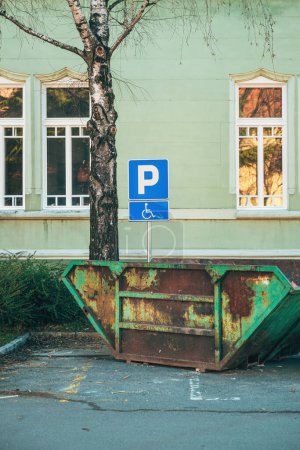 Foto de Antiguo contenedor de basura skip usado colocado en el estacionamiento reservado, imagen vertical - Imagen libre de derechos