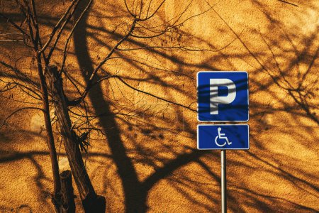 Téléchargez les photos : Panneau de stationnement accessible réservé aux personnes handicapées contre le mur jaune vif - en image libre de droit