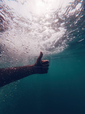 Téléchargez les photos : Homme gesticulant pouces vers le haut sous l'eau en eau profonde comme signe d'approbation et d'approbation, focalisation sélective - en image libre de droit