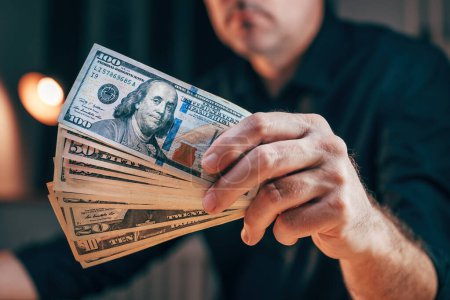 Photo for Closeup of male hand with dollar banknotes, businessman holding american money, handful of cash and ready to invest in entrepreneurial project, selective focus - Royalty Free Image