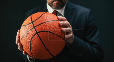Foto de Entrenador de baloncesto en elegante traje de negocios sosteniendo la pelota, enfoque selectivo - Imagen libre de derechos