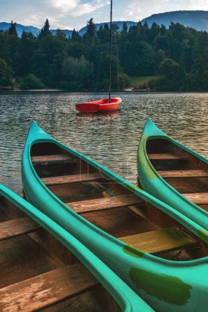 Foto de Tres canoas verdes y bote rojo en el lago Bohinj, enfoque selectivo - Imagen libre de derechos