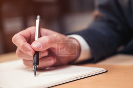 Foto de Primer plano de la mano masculina con bolígrafo hombre de negocios escribir notas y comentarios en cuaderno, enfoque selectivo - Imagen libre de derechos