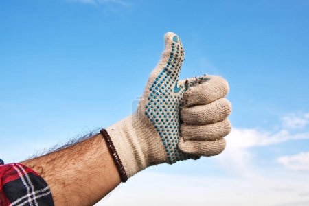 Foto de Jardinero con guantes de jardinería gestos pulgares hacia arriba como una recomendación y aprobación de la mano signo, enfoque selectivo - Imagen libre de derechos