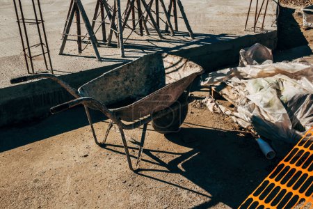 Téléchargez les photos : Vieille brouette sale chariot de poussette sur le chantier de construction, foyer sélectif - en image libre de droit