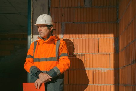 Téléchargez les photos : Portrait d'ingénieur en construction sur chantier, appuyé sur un mur inachevé - en image libre de droit