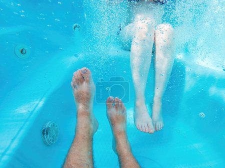 Téléchargez les photos : Couple dans un bain à remous, plan sous-marin de jambes masculines et féminines dans l'eau, mise au point sélective - en image libre de droit
