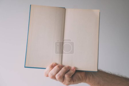 Foto de Libro de tapa dura maqueta páginas en blanco, mano masculina celebración de publicación impresa, enfoque selectivo - Imagen libre de derechos