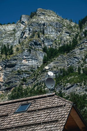 Foto de Techo de casa de montaña con antena parabólica debajo de las montañas rocosas de los Alpes Julianos en verano, enfoque selectivo - Imagen libre de derechos