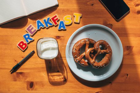 Téléchargez les photos : Smartphone, ordinateur portable et stylo sur la table de petit déjeuner avec bretzels et yaourts, vue sur le dessus - en image libre de droit