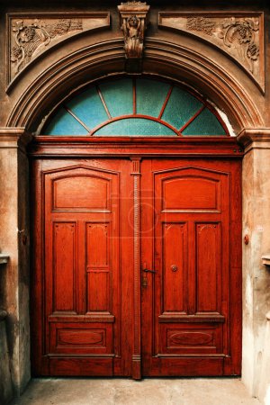 Foto de Masiva puerta de madera vintage como entrada a un antiguo edificio residencial con fachada decorada con hormigón fundido, imagen vertical - Imagen libre de derechos