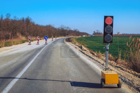 Foto de Señalización del semáforo durante el mantenimiento de la carretera, semáforo rojo para la regulación del tráfico, enfoque selectivo - Imagen libre de derechos