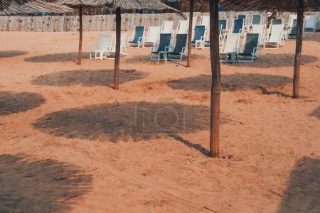 Téléchargez les photos : Parasols et chaises longues en paille roseau sur une plage de sable fin - en image libre de droit